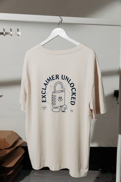 Cream branded t-shirt on a hanger with an 'Exclaimer Unlocked' print