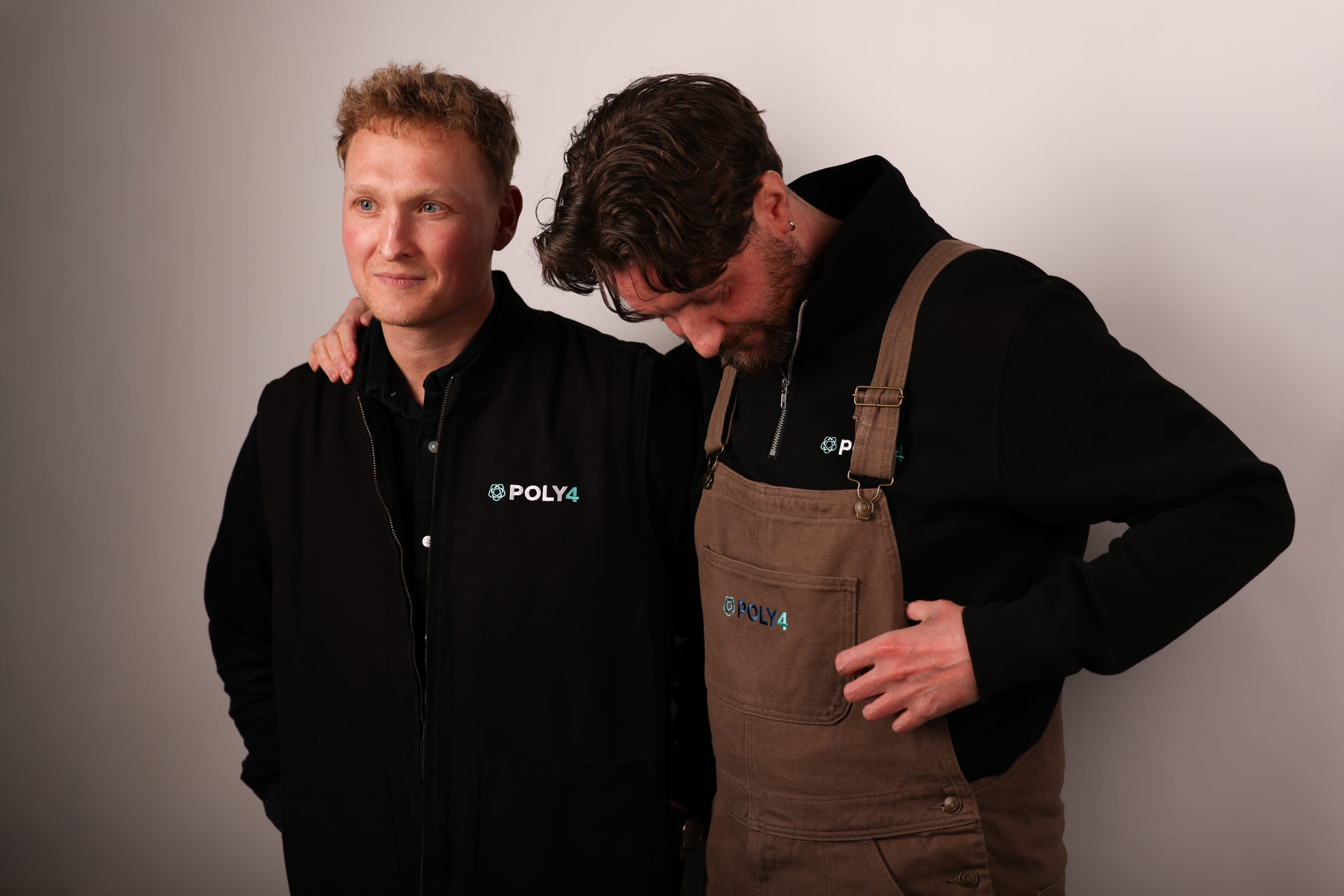 Two people in black and brown POLY4-branded workwear.