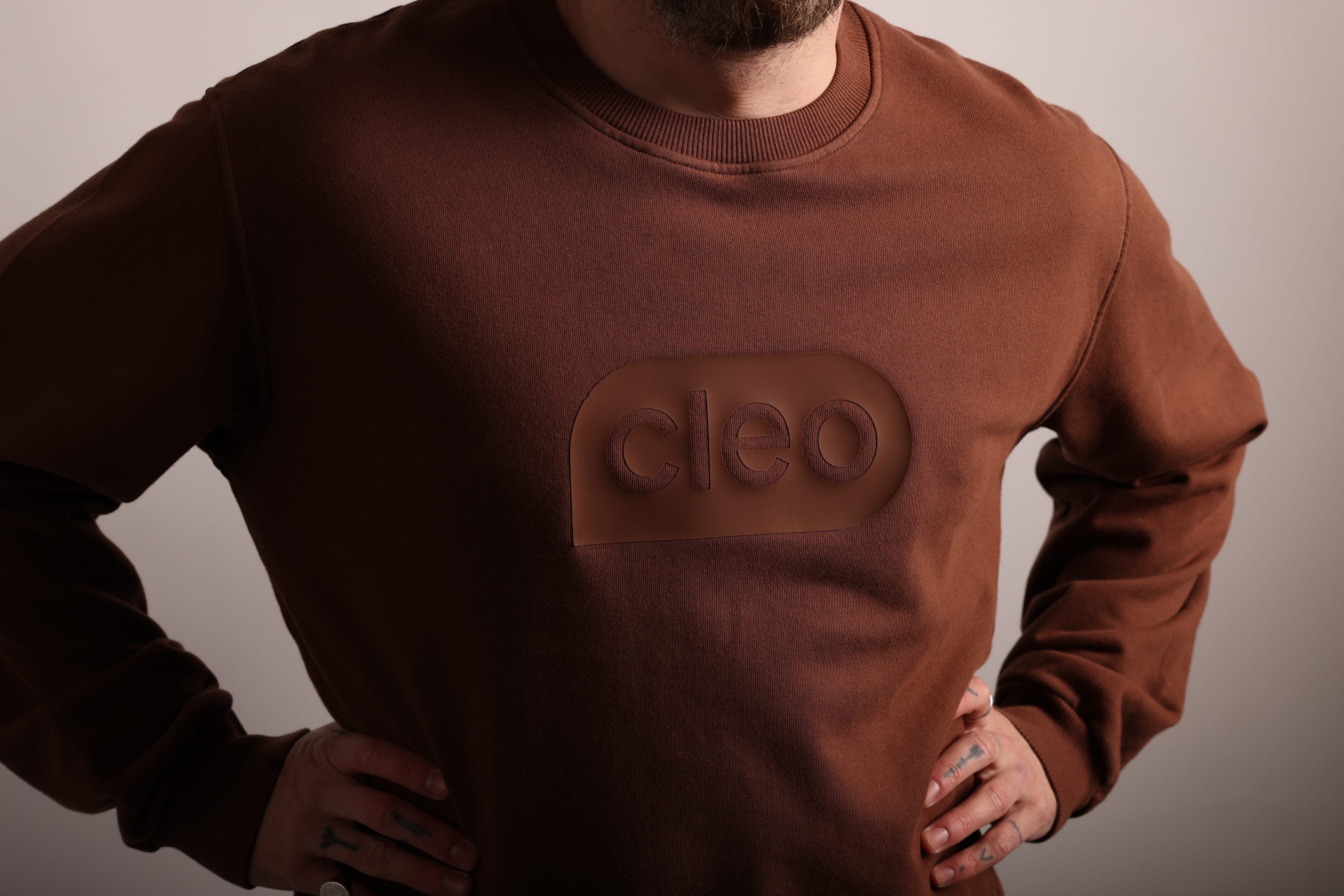 Brown crewneck sweatshirt with a tonal raised Cleo logo patch.